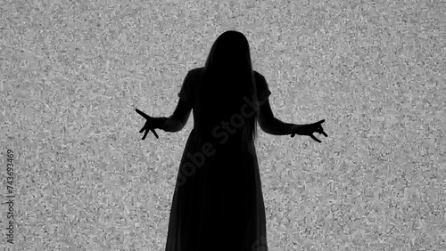Silhouette against digital television screen. Thriller scene spooky woman in dress posing like zombie in front of big digital screen with white noise.