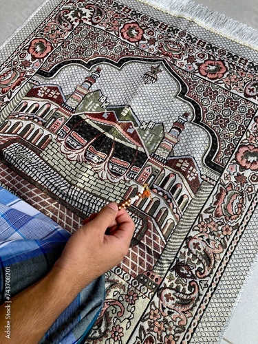 Close up of A portrait of an asian muslim man pray, the pray name is sholat, regards end of sholat. Using blue sarong and gray sajadah photo