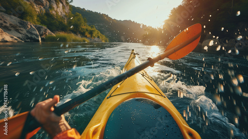  First-person perspective of a kayaker paddling through serene waters, with the sun's rays casting a warm glow over the scene, encapsulating the essence of outdoor adventure. © praewpailyn