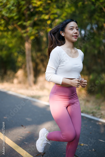 Cheerful woman enjoys jogging on the street in the warm morning sun.