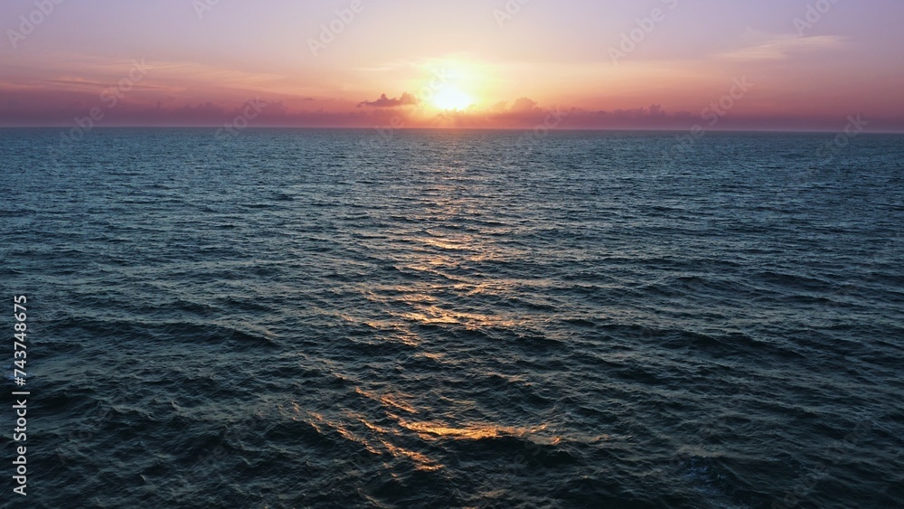 Aerial view over beautiful  ocean during  sunset. Top view to the ocean in summer day while sunset - closeup. Drone view of a Scenic slow motion ocean waves. Beautiful sunrise over ocean
