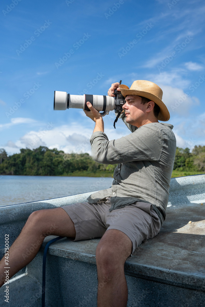 Obraz premium Photographer with telephoto lens with hat on a boat