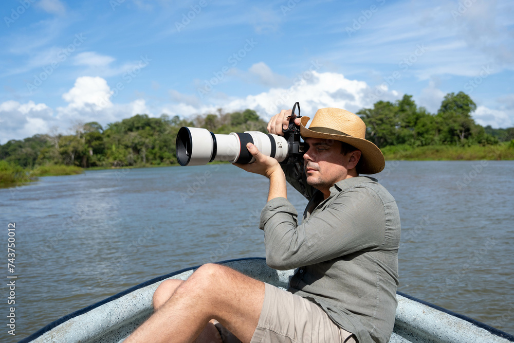 Obraz premium Photographer with telephoto lens with hat on a boat