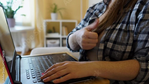 Smiling Caucasian woman working remotely on laptop sitting on couch, chatting online. The concept of remote work, online shopping, online work, happy family, digital lifestyle, online conference.