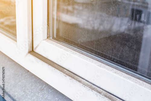 A woman in a rubber glove points to the mold. Plastic window and window sill in mold and dirt. Fungus and dampness at the wet window. Space for text. Shallow depth of field.