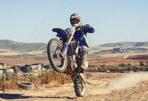 Motorcycle, action and balance of person with speed and skill for adrenaline and stunt with extreme sports outdoor. Competition, adventure and power with risk, biker riding on motorbike with wheelie