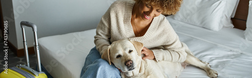 Принти на полотні banner of happy african american woman cuddling labrador near luggage in pet-fri