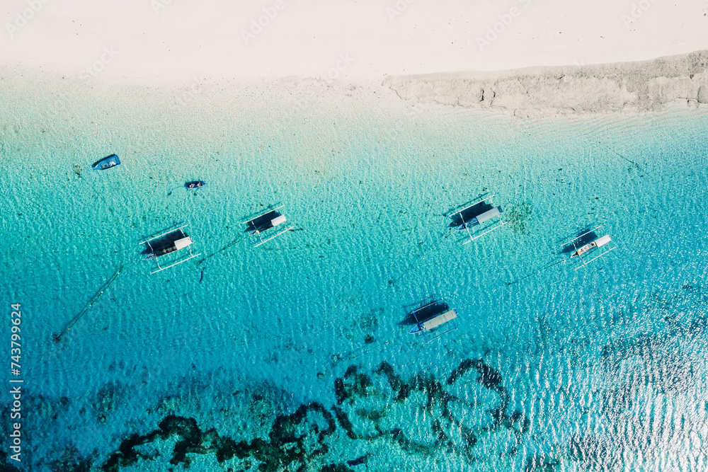 Boats in blue ocean and white sand beach on tropical island. Aerial view.