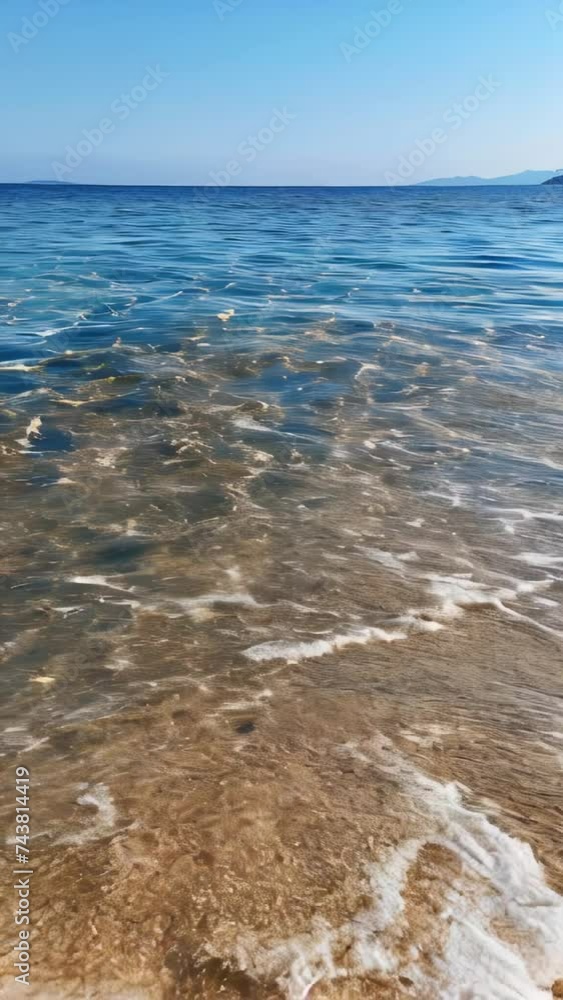 A coastline where gentle waves wash upon a sandy beach, in the dim light
