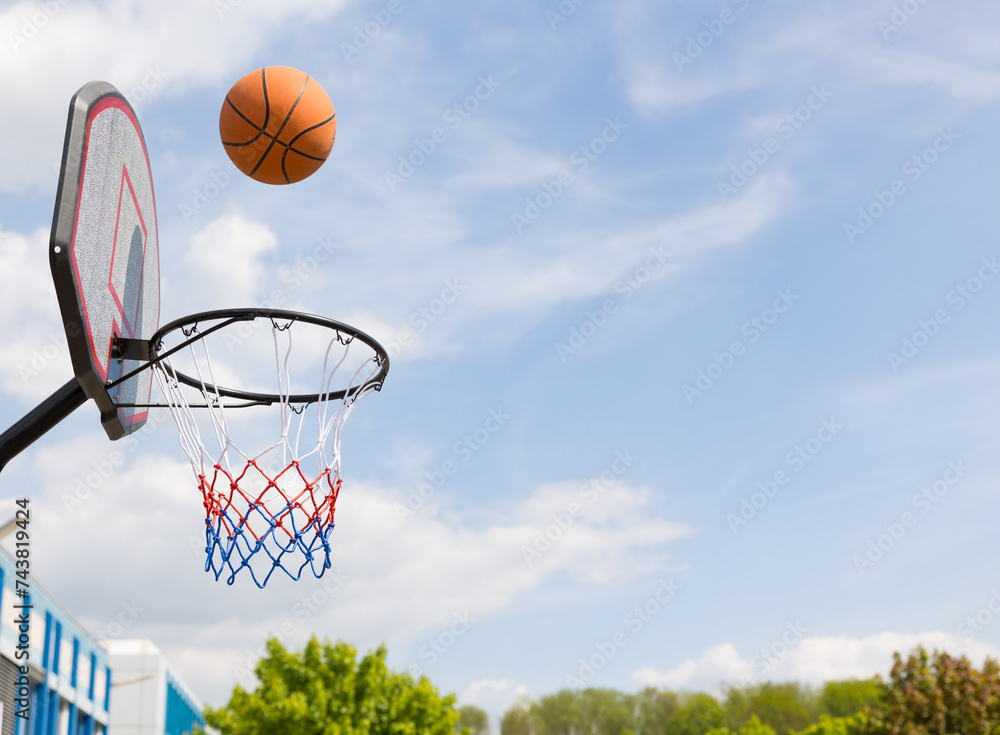 Basketballkorb mit Ball vor blauem Himmel