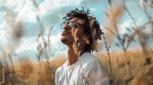Young black man in a field breathing in fresh air. Young man meditating in nature. Wellness and healing in nature. Diversity and inclusion in the wellness industry. photo