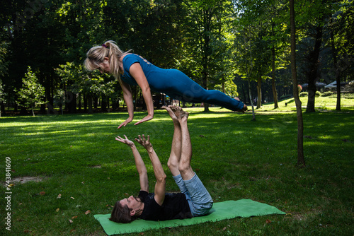 Boy and girl doing acro yoga outdoors in summer in public park