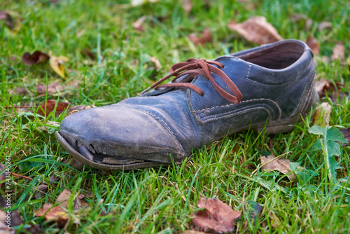 old torn shoe on the grass, there is garbage in nature, cluttering nature with clothes