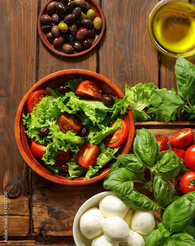 fresh salad with tomatoes and olives in a wooden bowl