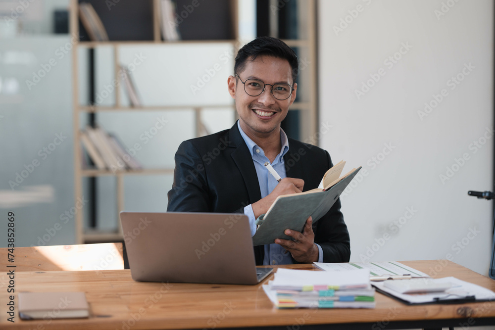 Fototapeta premium Joyful and Intelligent Entrepreneur Crafting Ideas with Laptop in Office Workspace.