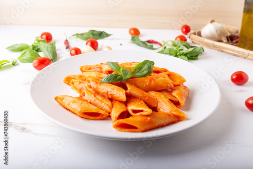 Pasta with fresh tomatoes sauce and basil. Penne with tomatoes served on a white background. Italian typical dish.