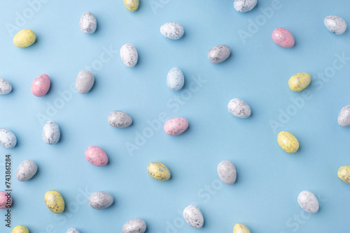 Festive Easter background. Multicoloured Easter eggs on a blue table. Top view.