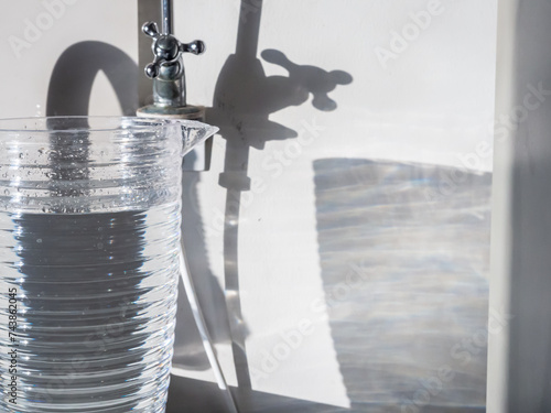 plastic pitcher contains drinking water cast light and shadow on the white wall, graphic concept