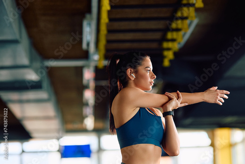 Young sportswoman stretching her arms while working out in gym.