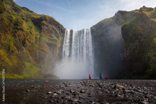 Group of tourists looking at the impressive Skogafoss waterfall in southern Iceland. Travel attractions and landmarks concepts.