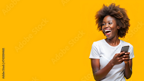 Mujer afro sorniente utilizando su smartphone. Chica negra sobre fondo amarillo. Persona utilizando tecnología con espacio de copia. photo