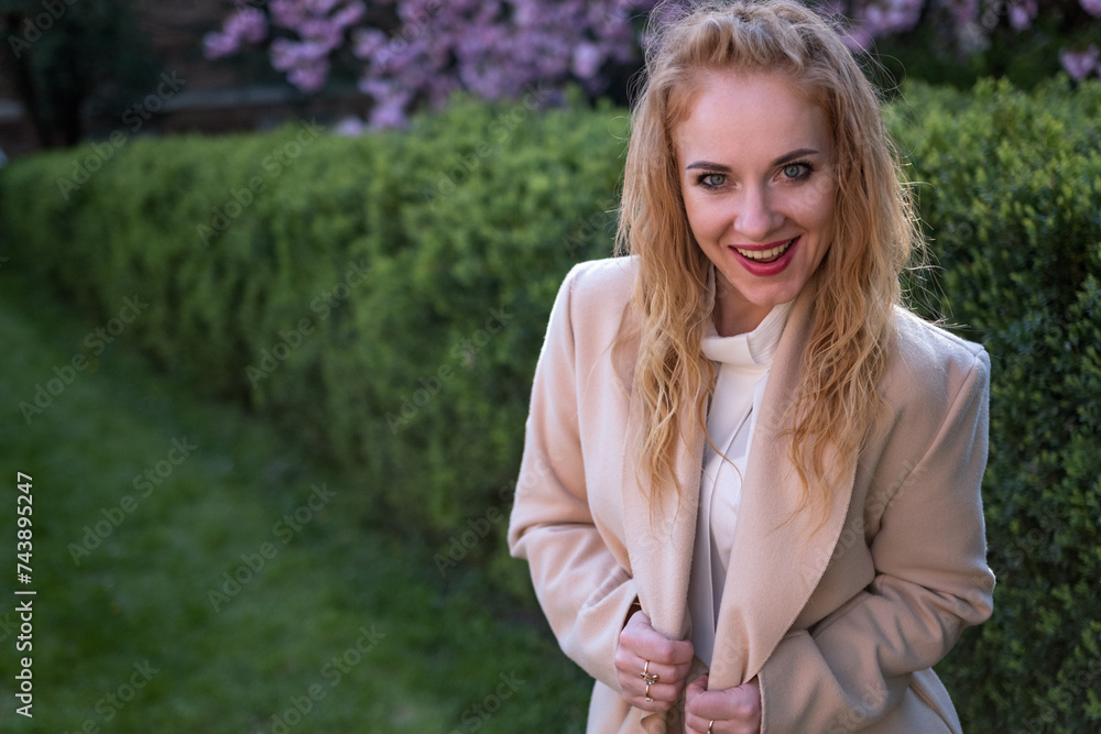Portrait of ginger-tressed beauty in beige coat in park smiling and looking at the camera. Girl with crazy look. Portrait of ginger-tressed beauty in beige coat in park smiling and looking at the camera. Girl with crazy look.