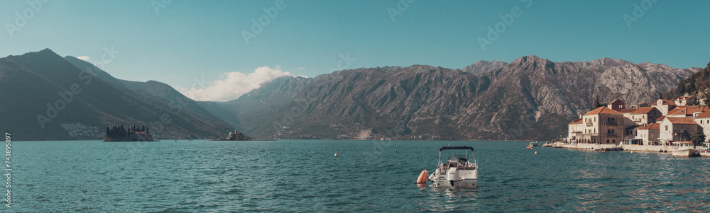 Fjord, small islands, boat and mountains seen from beach, Perast, Montenegro