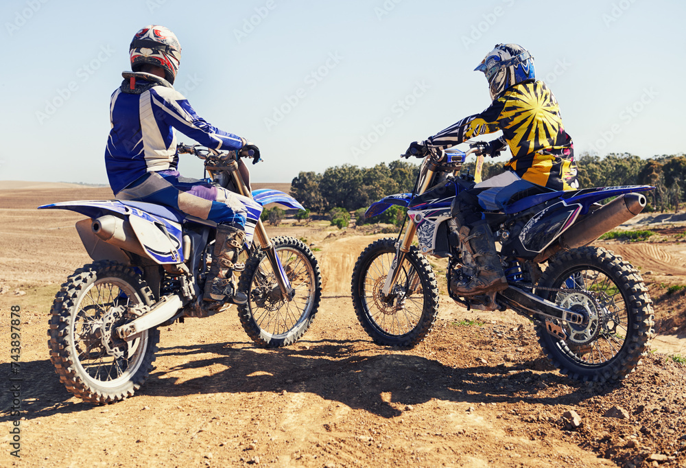 Rear view, sport or racer on motorcycle outdoor on dirt road with relax after driving, challenge or competition. Motocross, motorbike or dirtbike driver and helmet on offroad course or path at rally Rear view, sport or racer on motorcycle outdoor on dirt road with relax after driving, challenge or competition. Motocross, motorbike or dirtbike driver and helmet on offroad course or path at rally