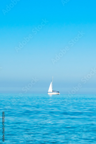white sailboat on the open sea near the horizon against a cloudless sky. Boat trip. place for text © Anton