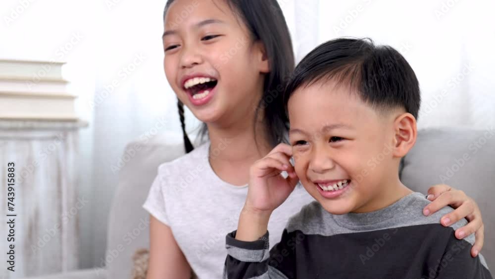 Asian sibling brother and sister share a laugh on a cozy sofa, happy children laugh bonding love relationship at home playtime, family lifestyle, enjoy carefree weekend, health care for kids concept Asian sibling brother and sister share a laugh on a cozy sofa, happy children laugh bonding love relationship at home playtime, family lifestyle, enjoy carefree weekend, health care for kids concept