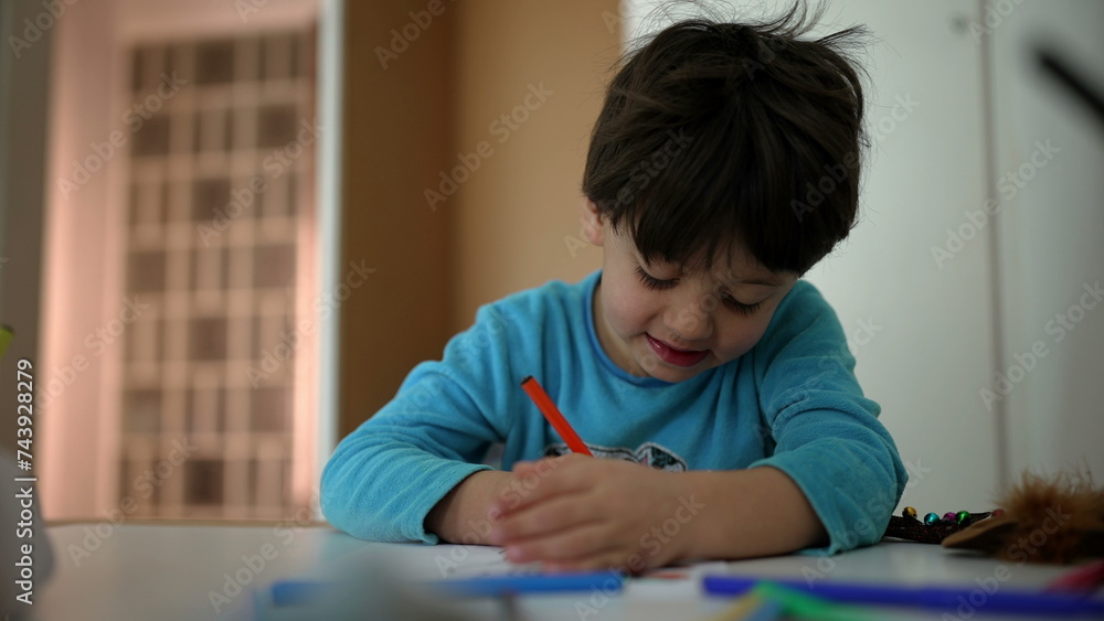 Concentrated little boy drawing at home before bedtime. Child coloring on paper in bedroom table. Childhood art leisure activity Concentrated little boy drawing at home before bedtime. Child coloring on paper in bedroom table. Childhood art leisure activity