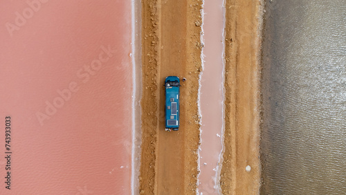 A green camper on a dirt road next to some pink salt flats © JoseMaria