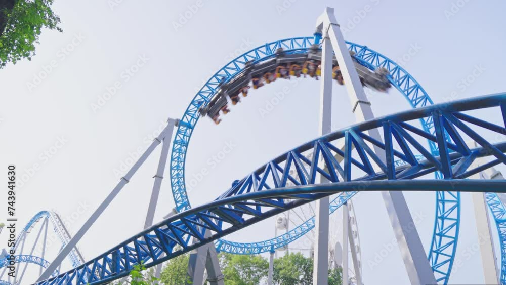 Roller coaster Ride against blue sky. Roller coaster in the amusement park. Cheerful entertainments in park of attractions Roller coaster Ride against blue sky. Roller coaster in the amusement park. Cheerful entertainments in park of attractions