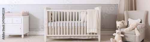 A cozy, neutral nursery with a crib, a changing table, a rocking chair, and a plush teddy bear.