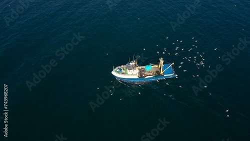 Aerial view to a fishing vessel in sea and many seagulls