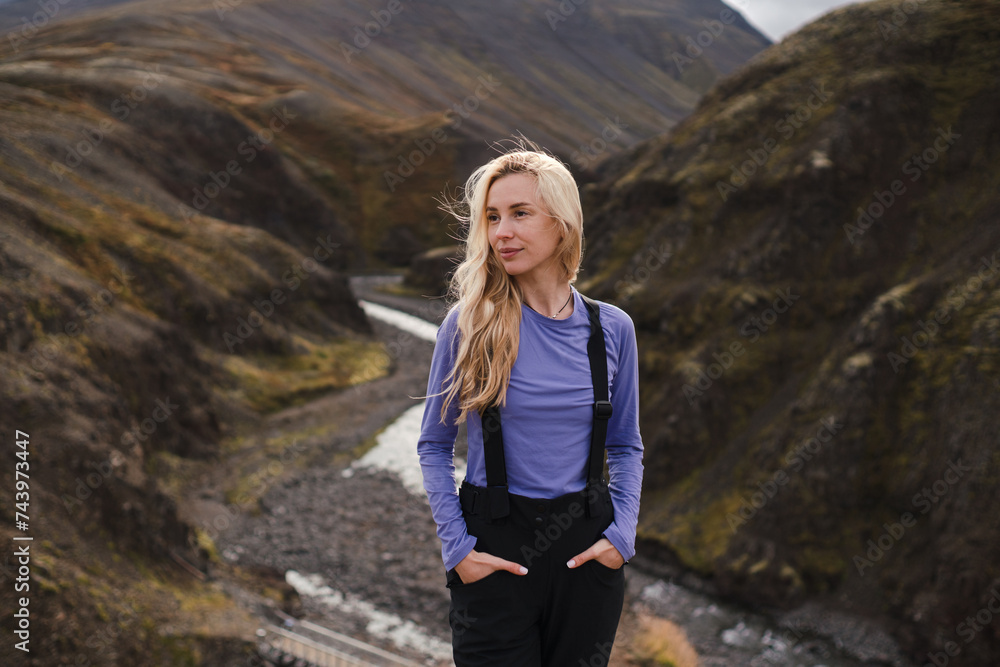 Traveling and exploring Iceland landscapes and travel destinations. Young traveler enjoying the view of beautiful nature. Female tourist watching spectacular scenery. Summer tourism by Atlantic ocean Traveling and exploring Iceland landscapes and travel destinations. Young traveler enjoying the view of beautiful nature. Female tourist watching spectacular scenery. Summer tourism by Atlantic ocean