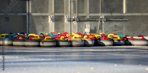 curling stones assembled on the ice near entrance to skating rink