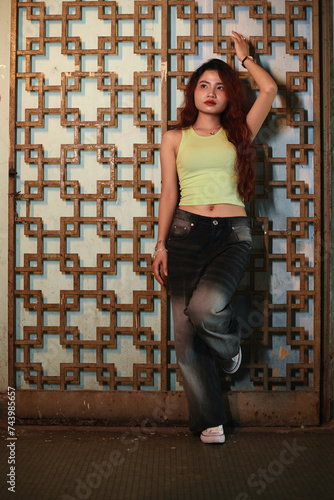 Young woman posing at painted decorative metal panel
