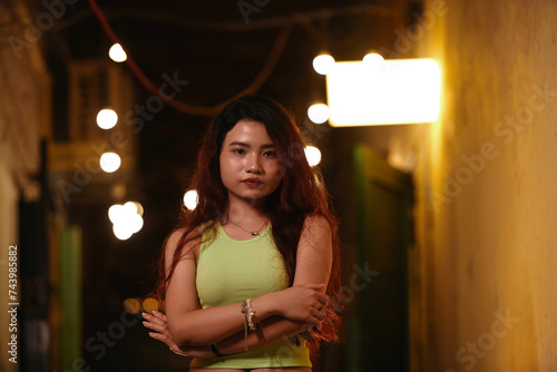 Portrait of young Vietnamese woman standing in corridor of old building enlighten with dim lights