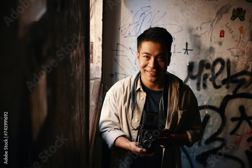 Portrait of cheerful photographer with old camera standing at window of abandoned building