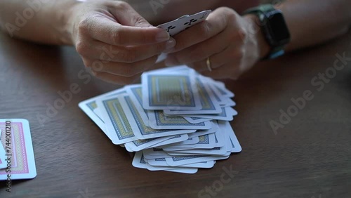 A woman is separating playing cards based on their deck colors on a wooden table