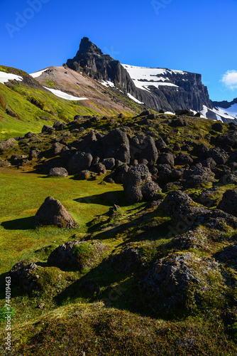 The green, boulder-filled valley on the Stórurð hiking trail, surrounded by the jagged Dyrfjöll Mountains, East Fjords, Iceland. photo