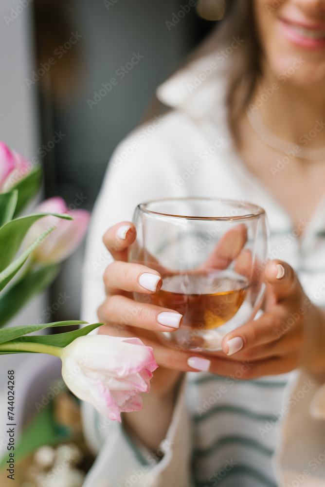 Close up of a glass of tea in the hands of a young woman