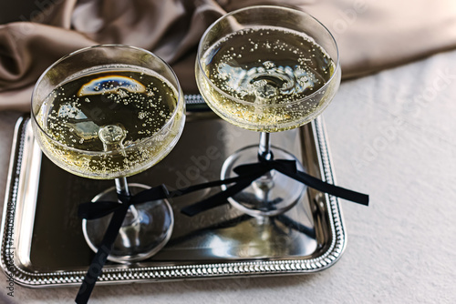 Two coupe glassed with sparkling wine decorated with satin bows