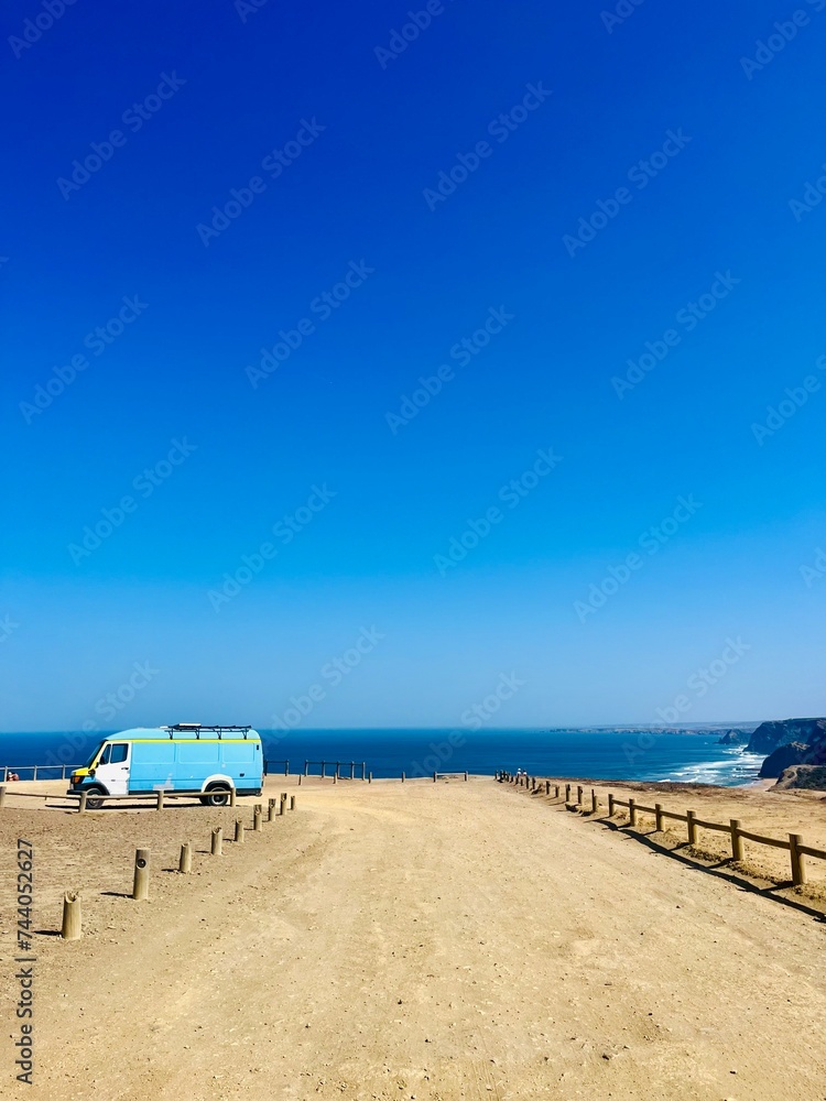 Vintage camper parked at the ocean coast, blue ocean horizon