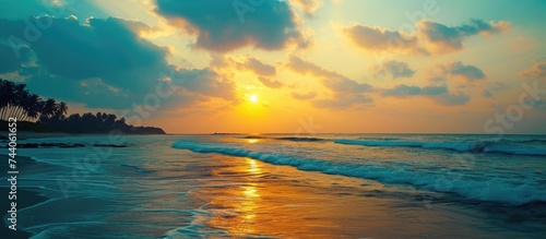 Experience the majestic beauty of the sun setting over the ocean on Keral Beach, creating a captivating scene. © AkuAku