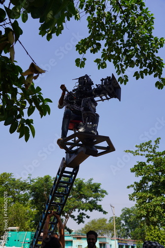 A cameraman riding a crane with a camera and shooting, camera on the street, cameraman shooting a movie