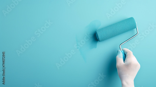 Hand painting wall with roller brush. Person applying bright blue paint to a wall with a roller. Banner template with copy space. Home improvements, renovations background texture.