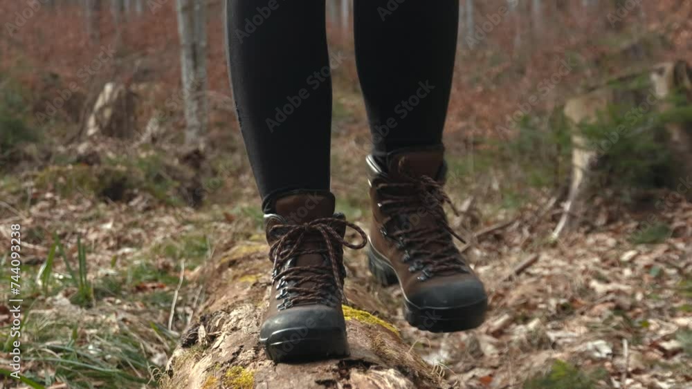 Close up of woman's legs wearing brown boots and black pants walking on a fallen tree in the forest Close up of woman's legs wearing brown boots and black pants walking on a fallen tree in the forest