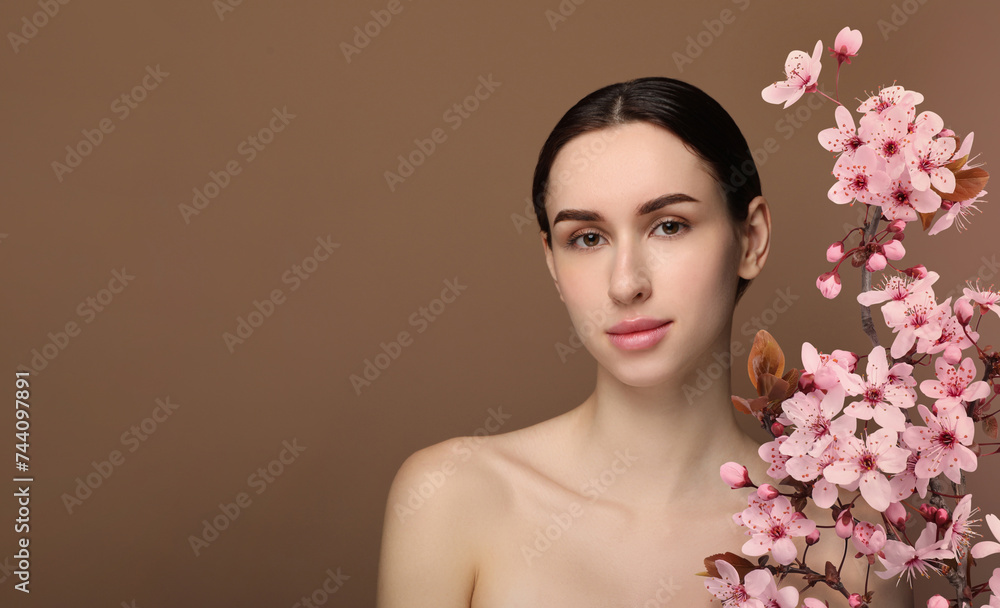Beautiful woman with smooth skin and flowers on brown background. Space for text Beautiful woman with smooth skin and flowers on brown background. Space for text